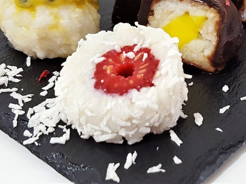 Veganer Sushi-Dessert mit Himbeere, Mango und Kokos auf Schieferplatte.