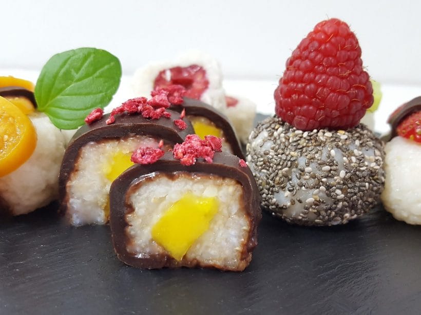 Ausgefallene, süße Sushi-Kreationen mit exotischen Früchten und Schokolade auf schwarzem Schieferbrett.